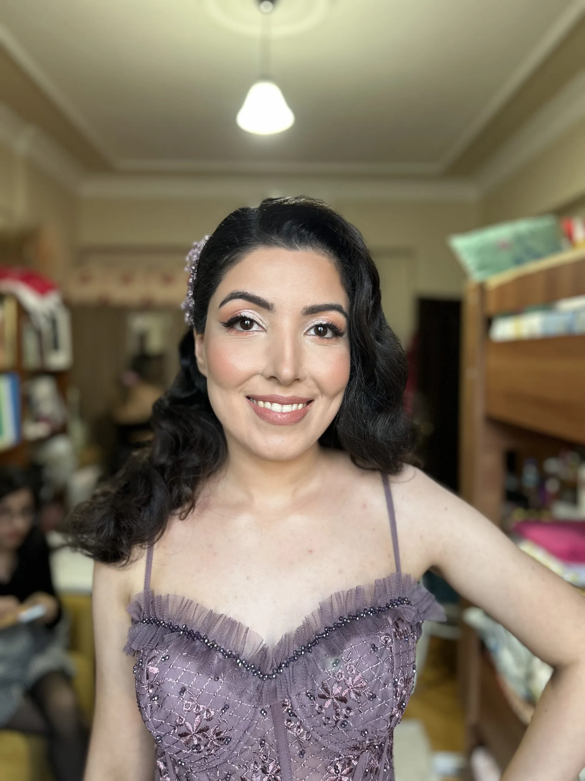 Kundin im fliederfarbenen Kleid nach dem Make-up für eine Feier